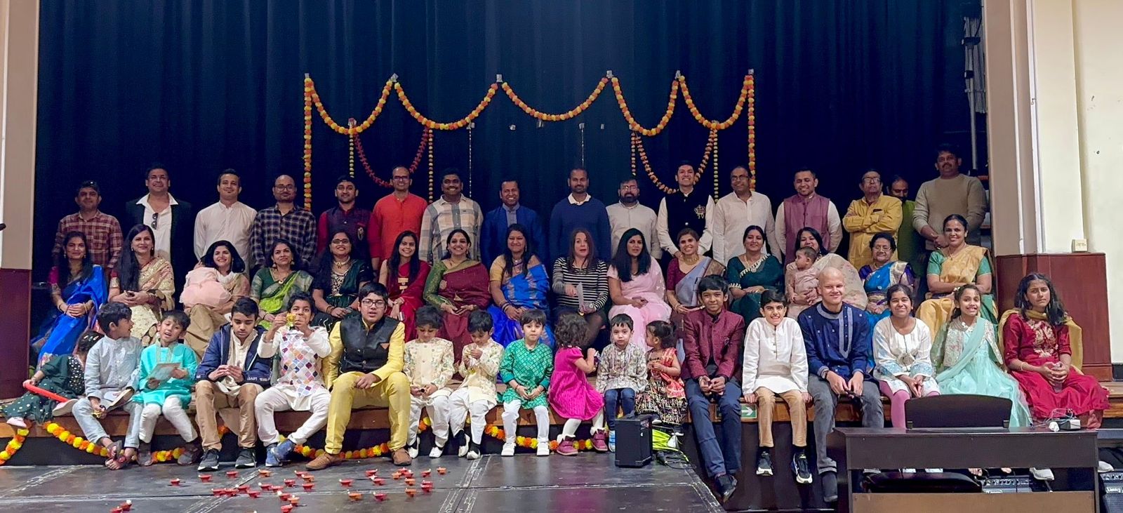 The Dharmik Fusion community gathered on stage under marigold garlands