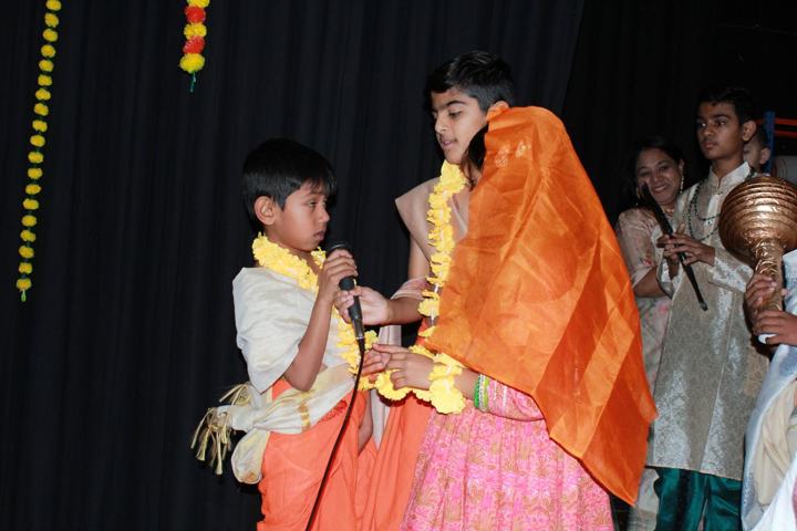 Children in traditional costume speaking on stage