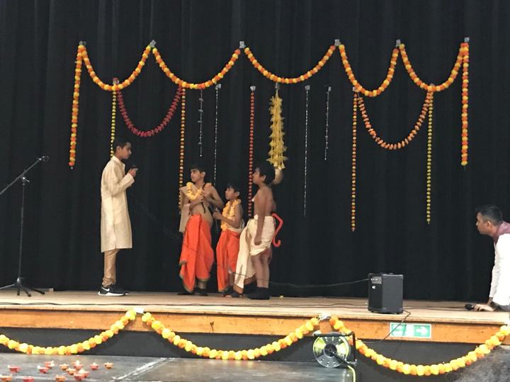 Children performing a play on a stage decorated with marigold garlands