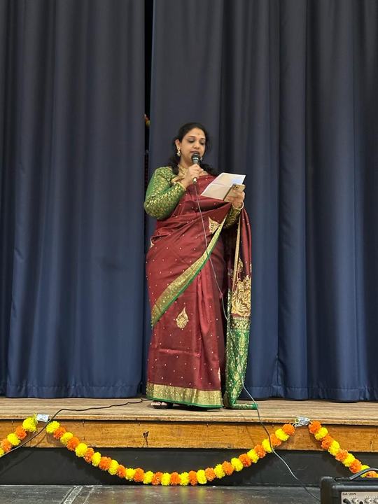 A woman in a sari giving a speech on stage